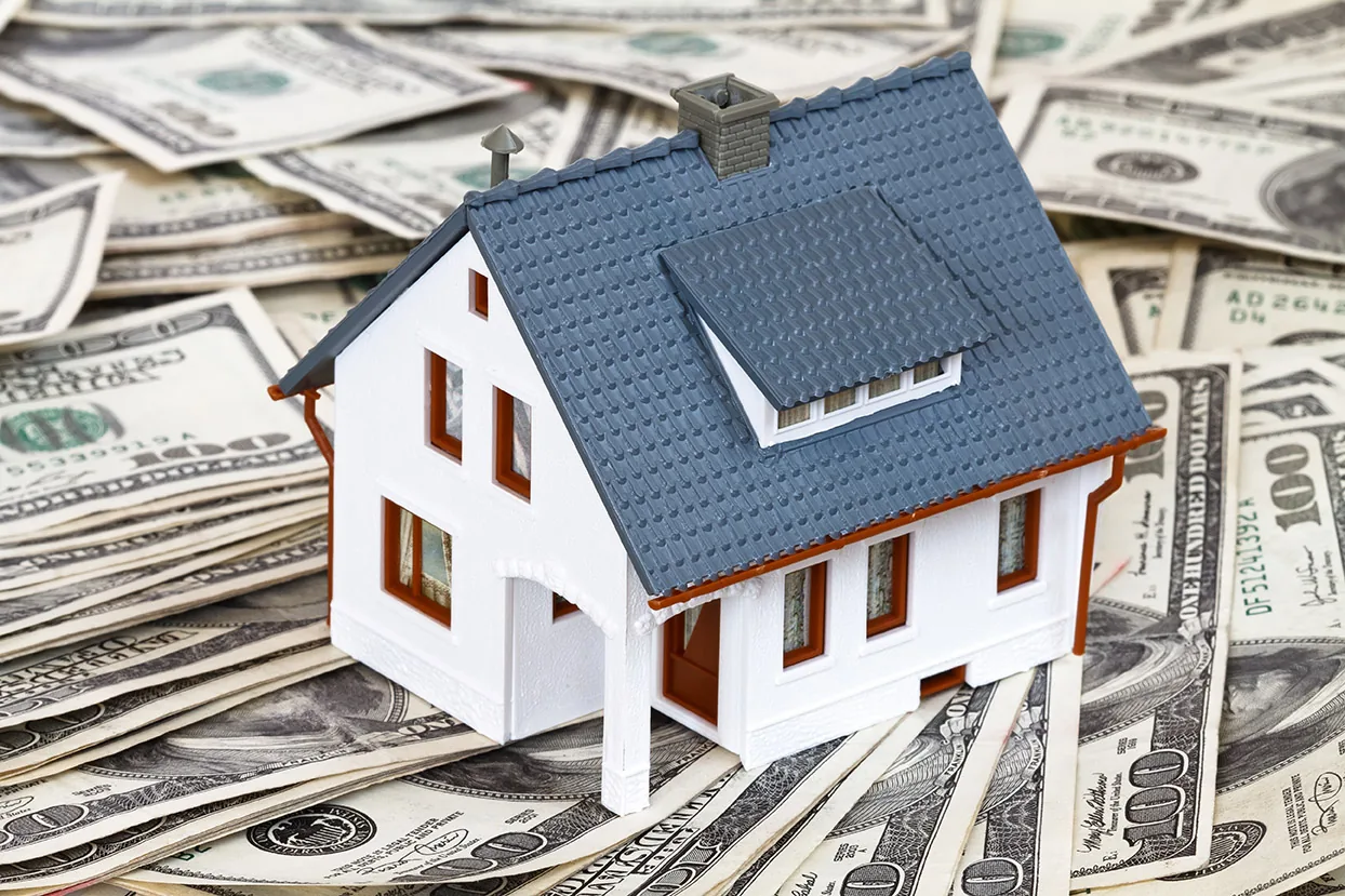 Model home resting on U.S. currency
